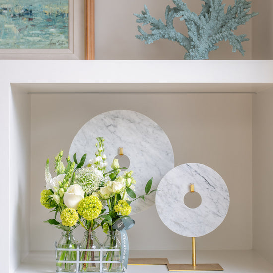Decorative shelf with a floral arrangement, marble ornaments, and a framed painting