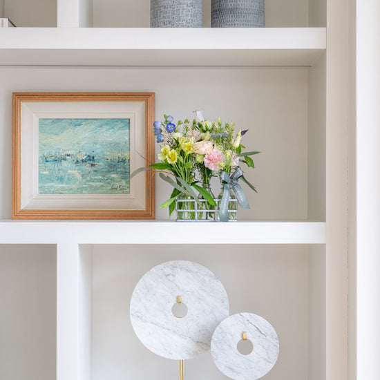 Decorative shelf with vases, a framed painting, and a floral arrangement