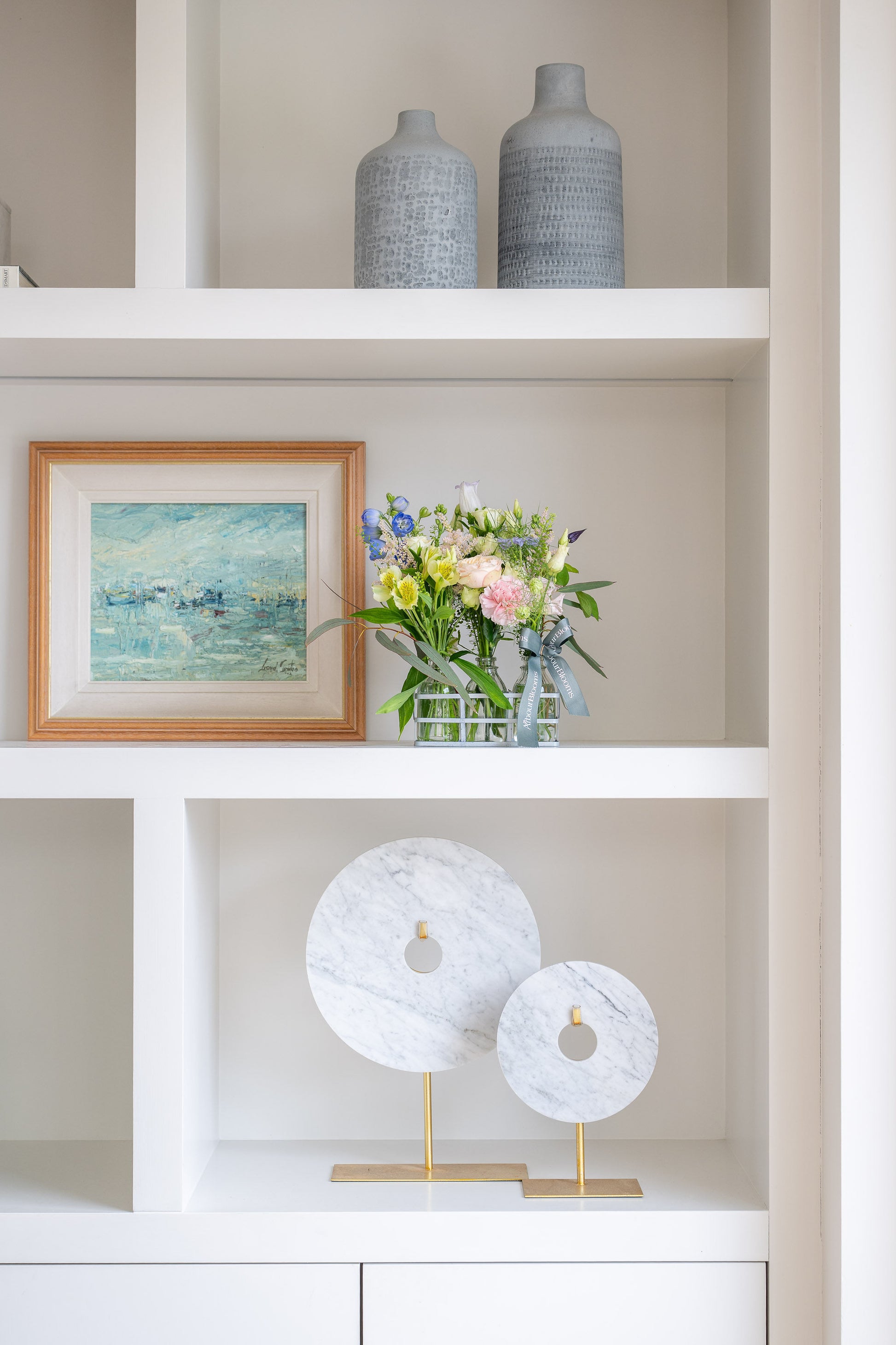 Decorative shelf with vases, a framed painting, and a floral arrangement