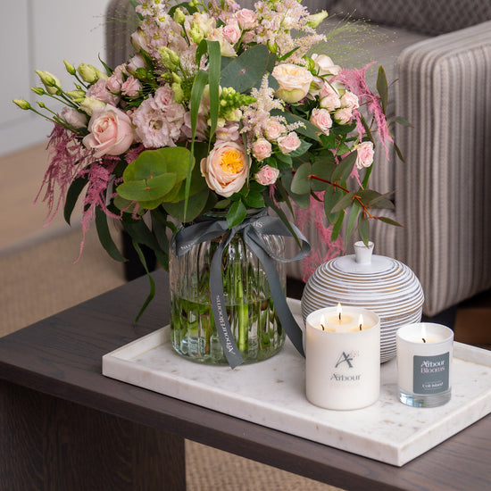 Floral arrangement on a coffee table with candles and a decorative jar