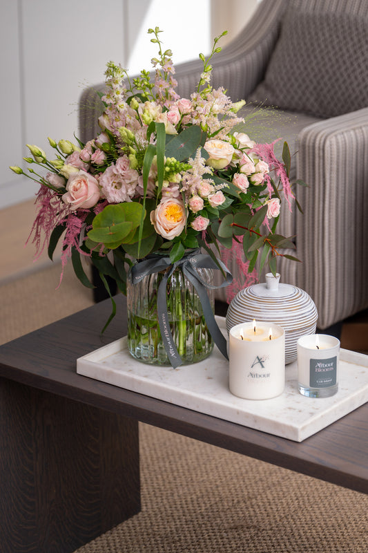 Floral arrangement on a coffee table with candles and a decorative jar